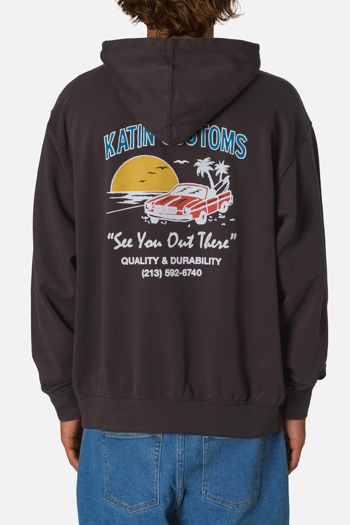 Person wearing a black hoodie with a graphic design on the back, standing against a white background.