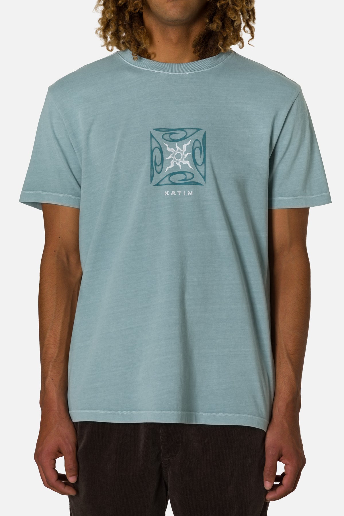 Person wearing a light blue t-shirt with a logo on a white background
