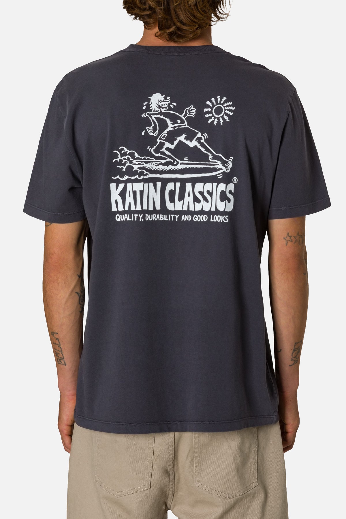 Person wearing a navy blue t-shirt with white graphics and text on the back, on a plain background.