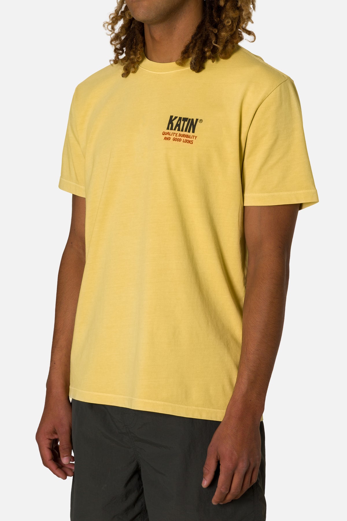 Person wearing a yellow t-shirt with a brand logo on a white background