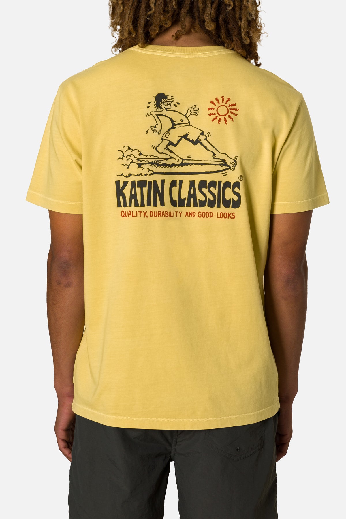 Person wearing a yellow t-shirt with a graphic design and text on the back.