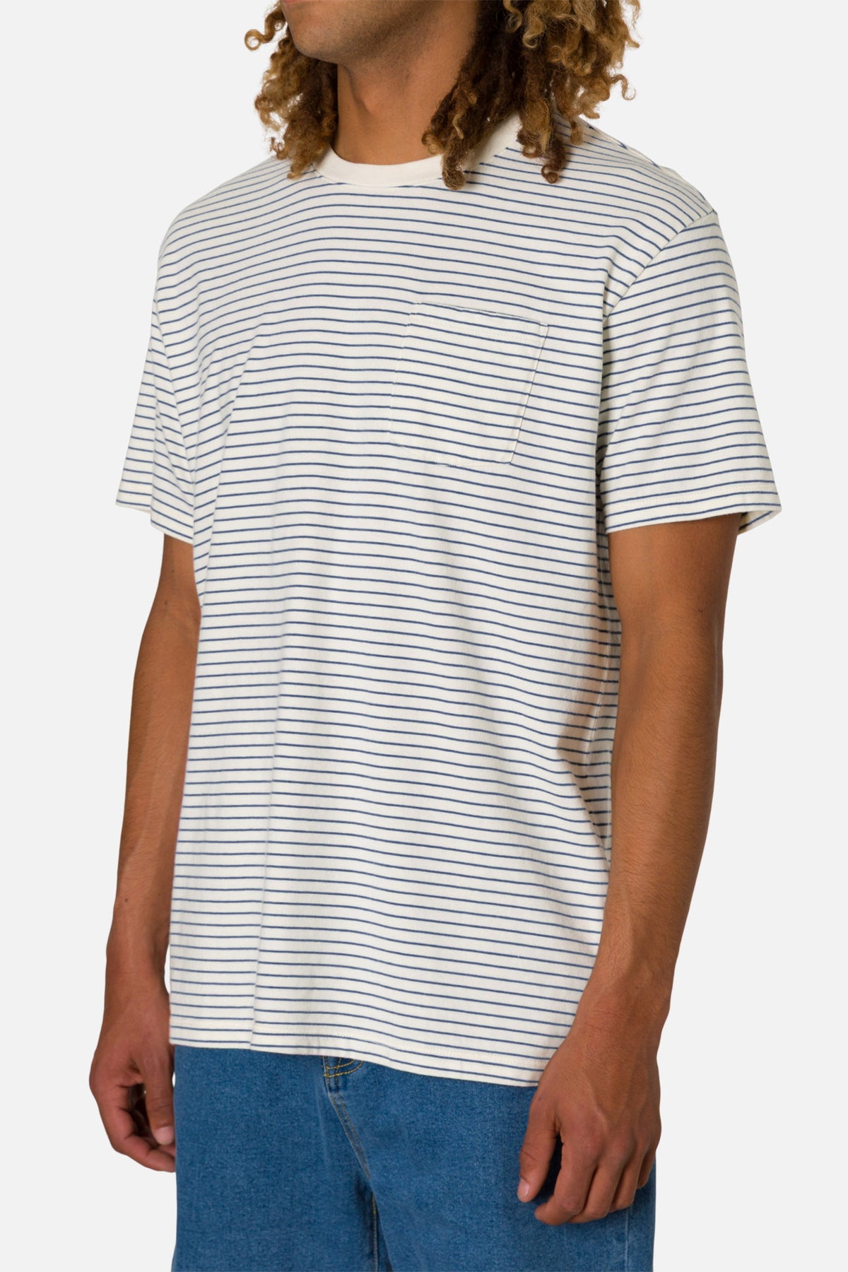 Person wearing a white t-shirt with thin black stripes and blue jeans on a white background