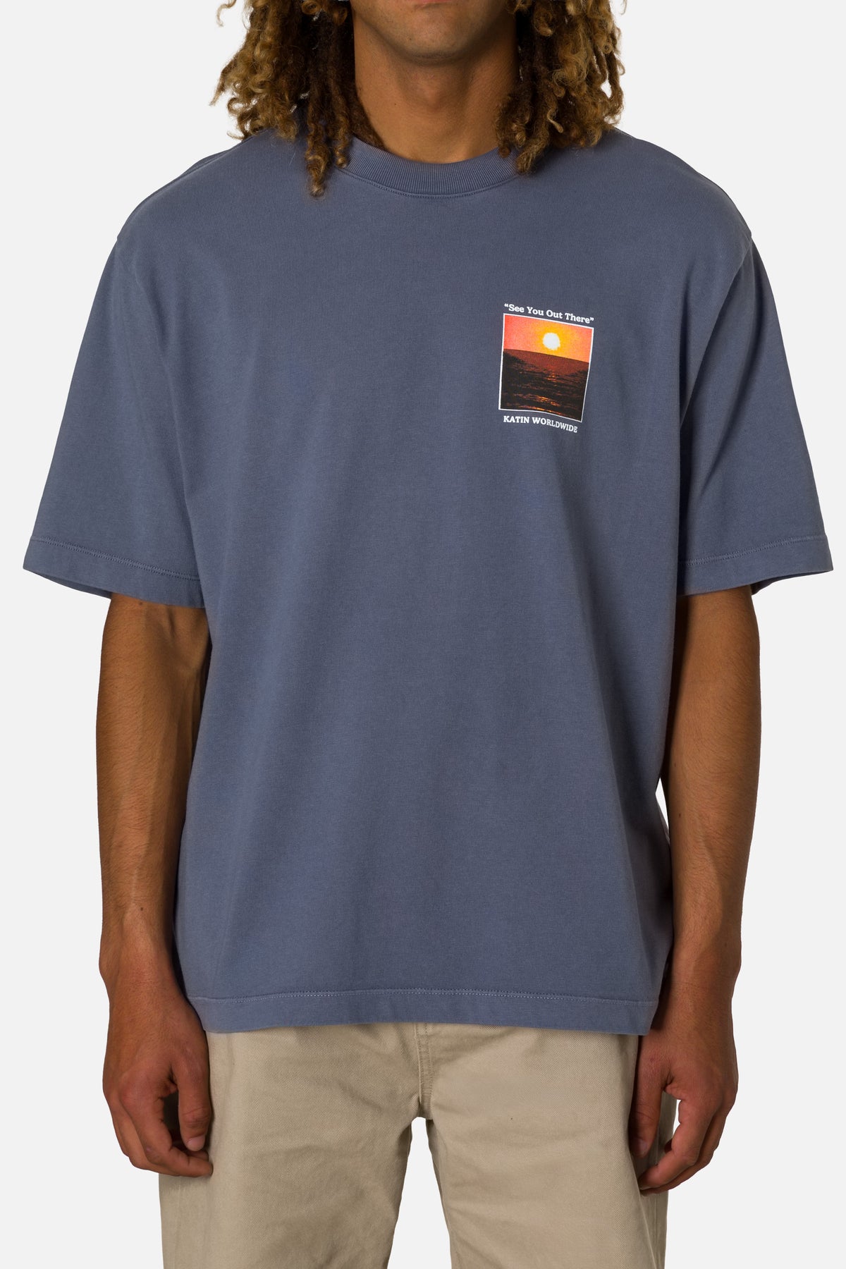 Person wearing a blue t-shirt with a graphic design on a plain background