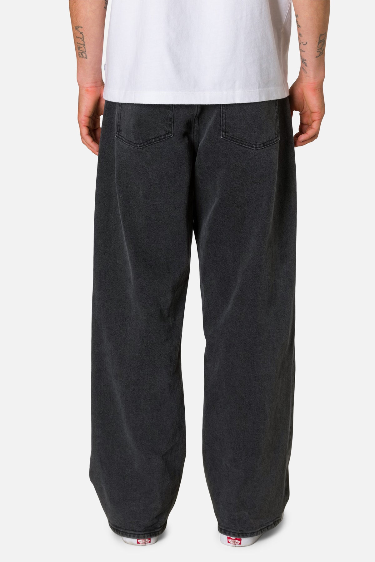 Person wearing black pants and a white shirt on a plain background