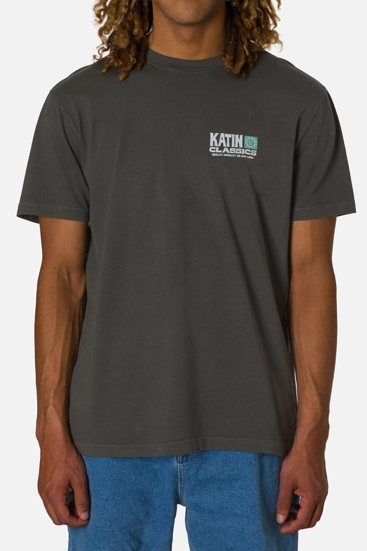Person wearing a dark gray t-shirt with a logo on a white background