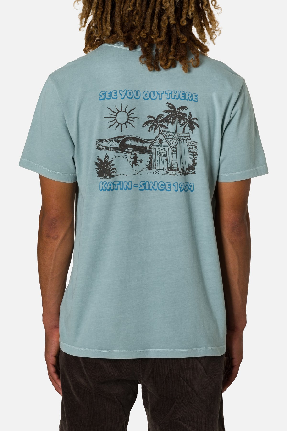 Person wearing a light blue t-shirt with a graphic design on the back, standing against a plain background.