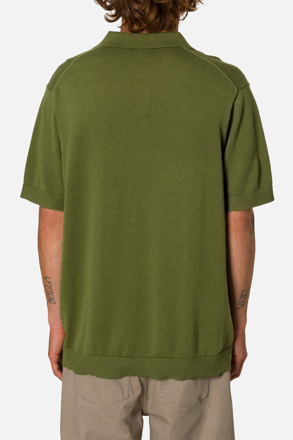 Person wearing a green polo shirt on a white background