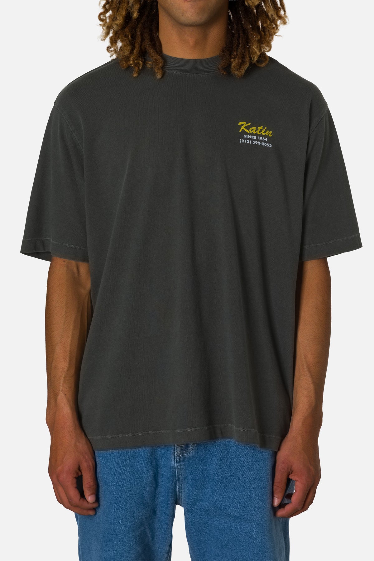 Person wearing a dark gray t-shirt with a logo on a plain background