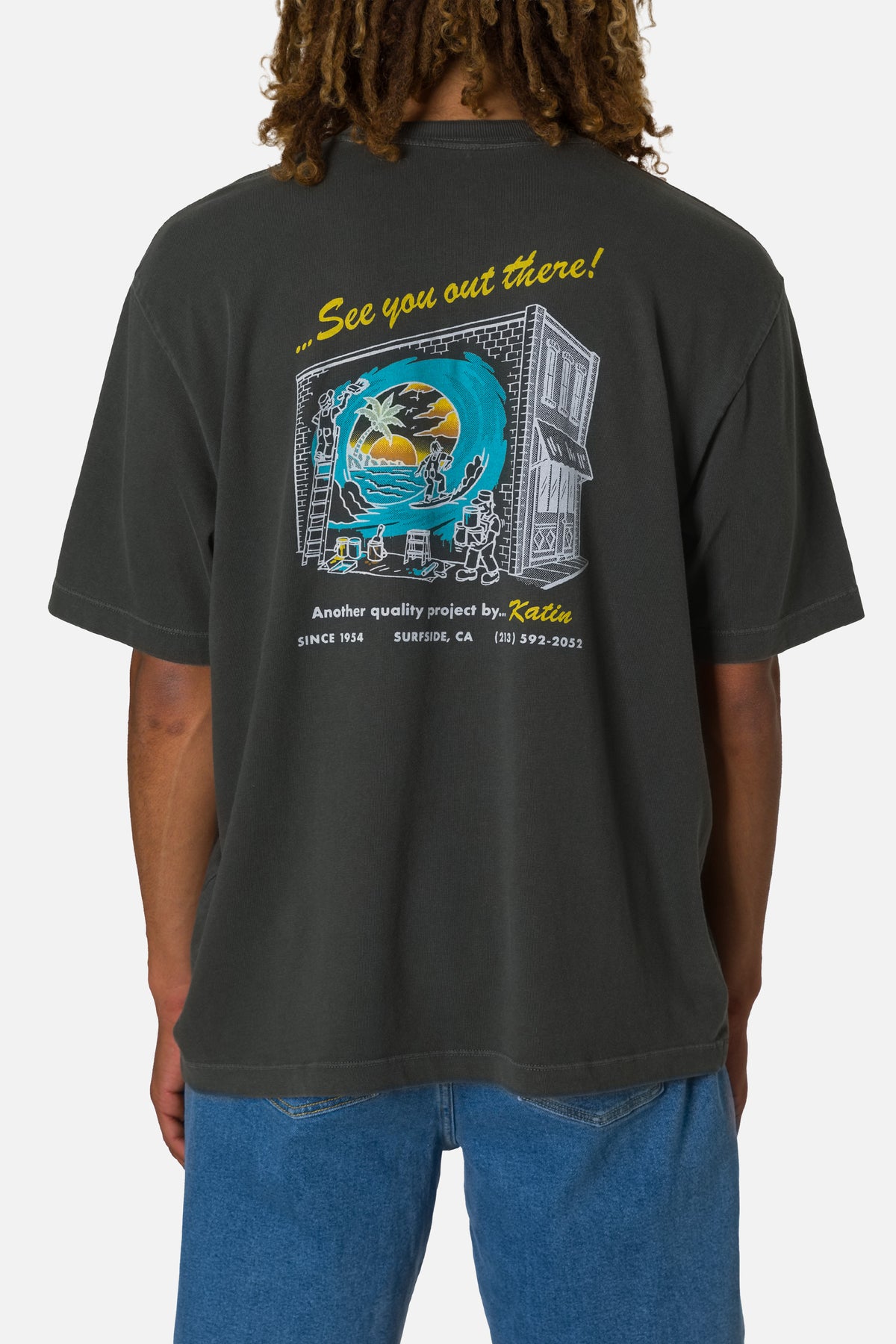 Person wearing a black t-shirt with a graphic design on the back, standing against a white background.