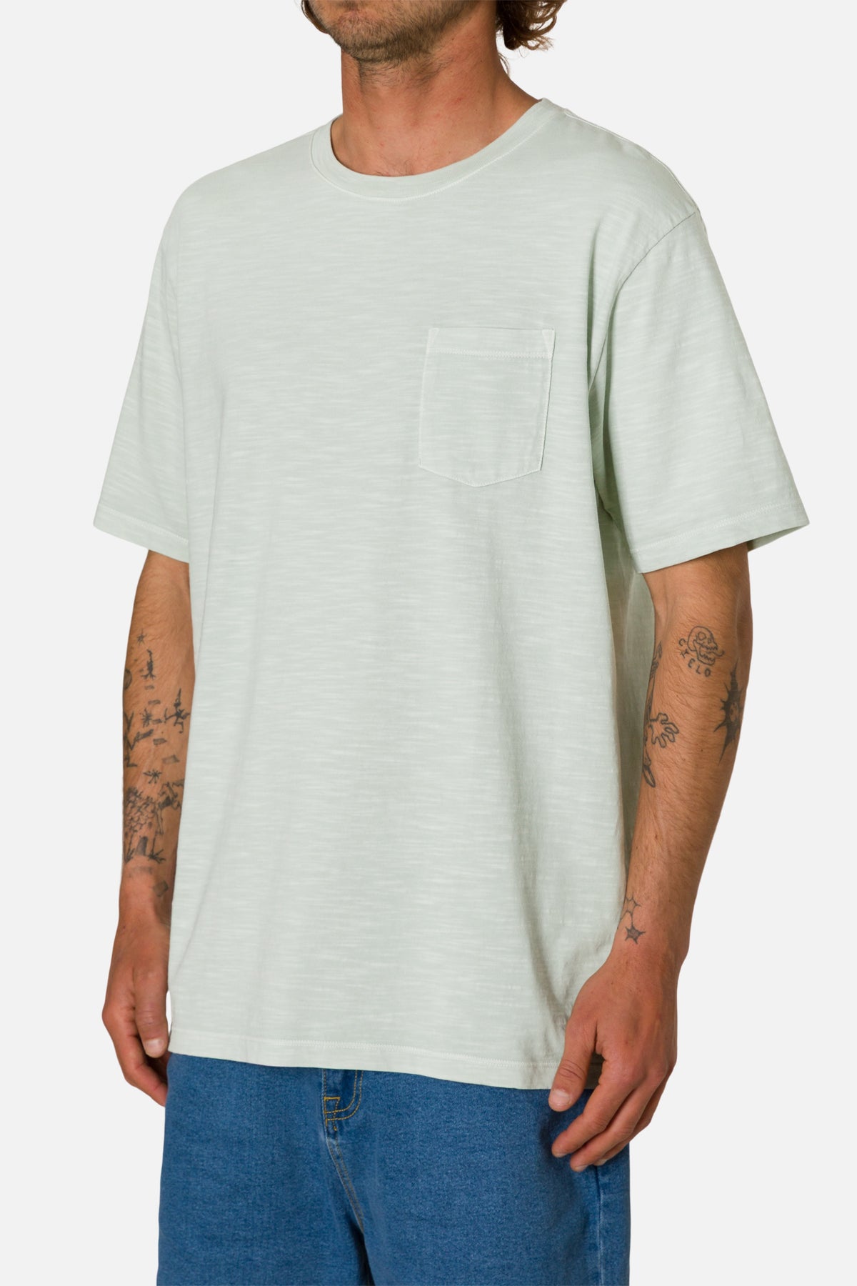 Person wearing a light green t-shirt and blue jeans on a white background