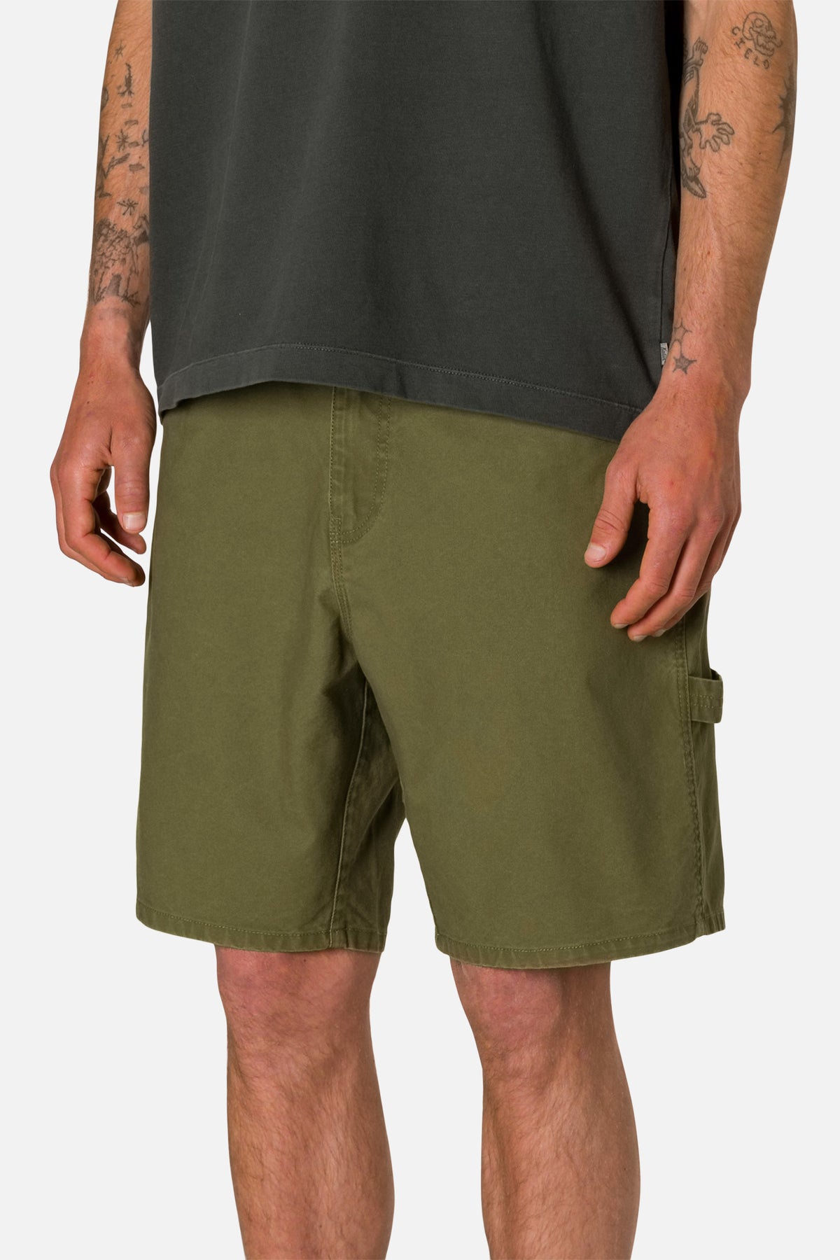 Side view person wearing Olive shorts and a black shirt on a plain background