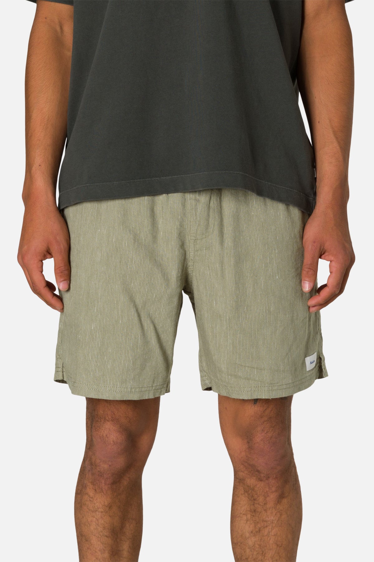 Person wearing green shorts and a black shirt on a white background
