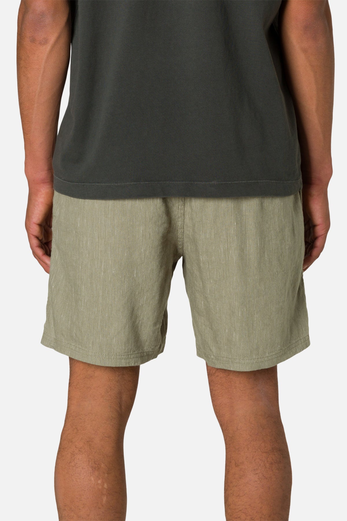 Person wearing green shorts and a dark shirt on a white background