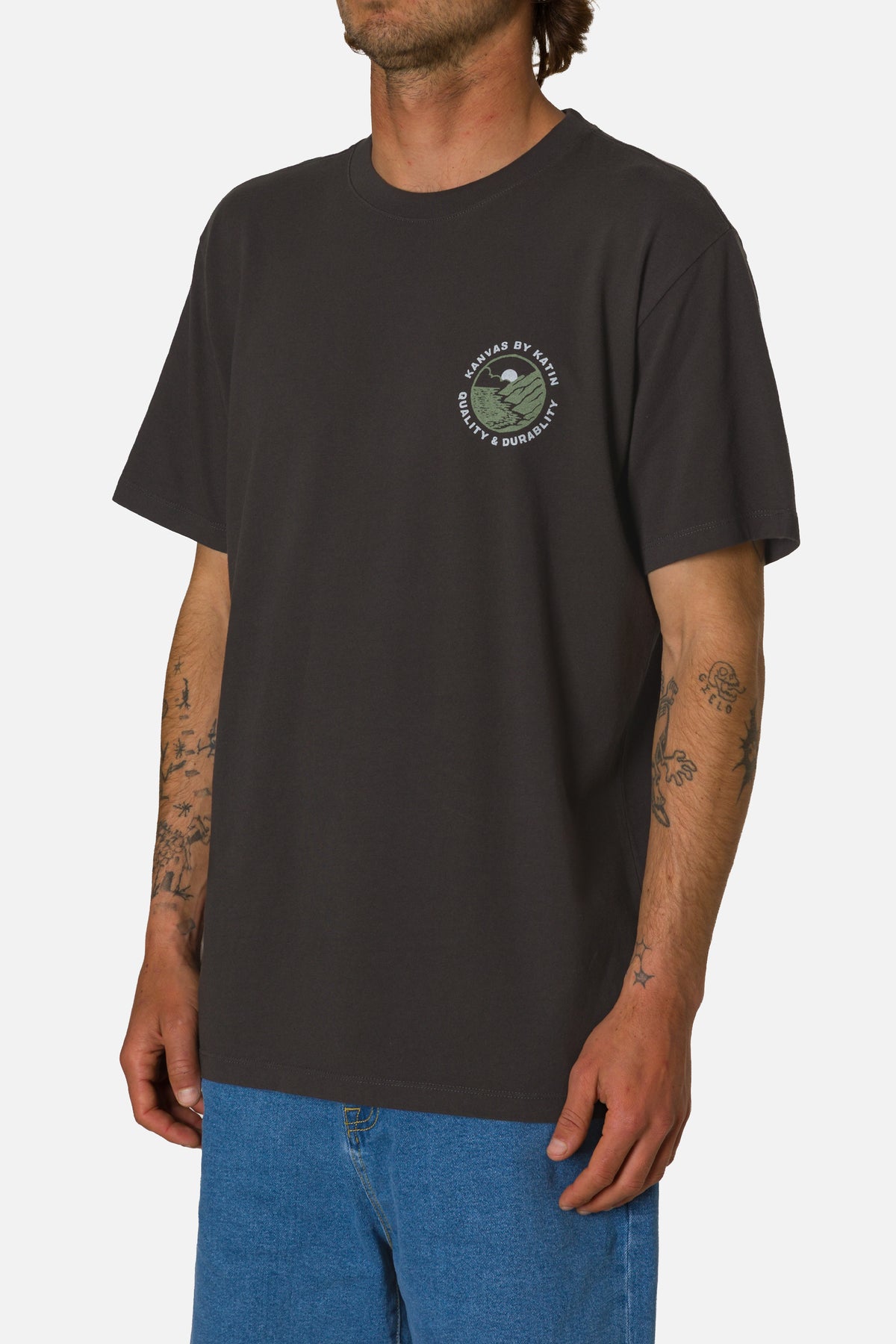 Person wearing a black t-shirt with a logo on a plain background