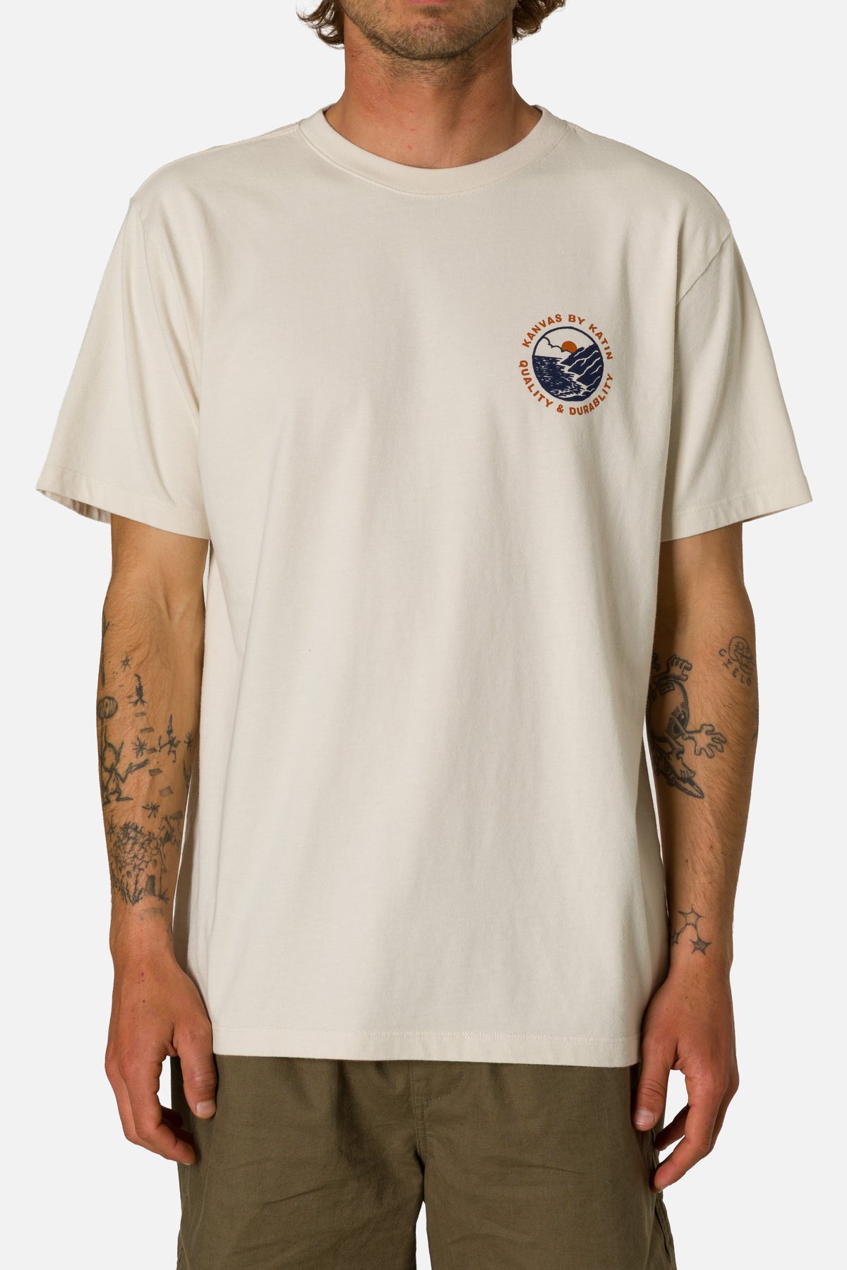 Person wearing a beige t-shirt with a logo on a white background