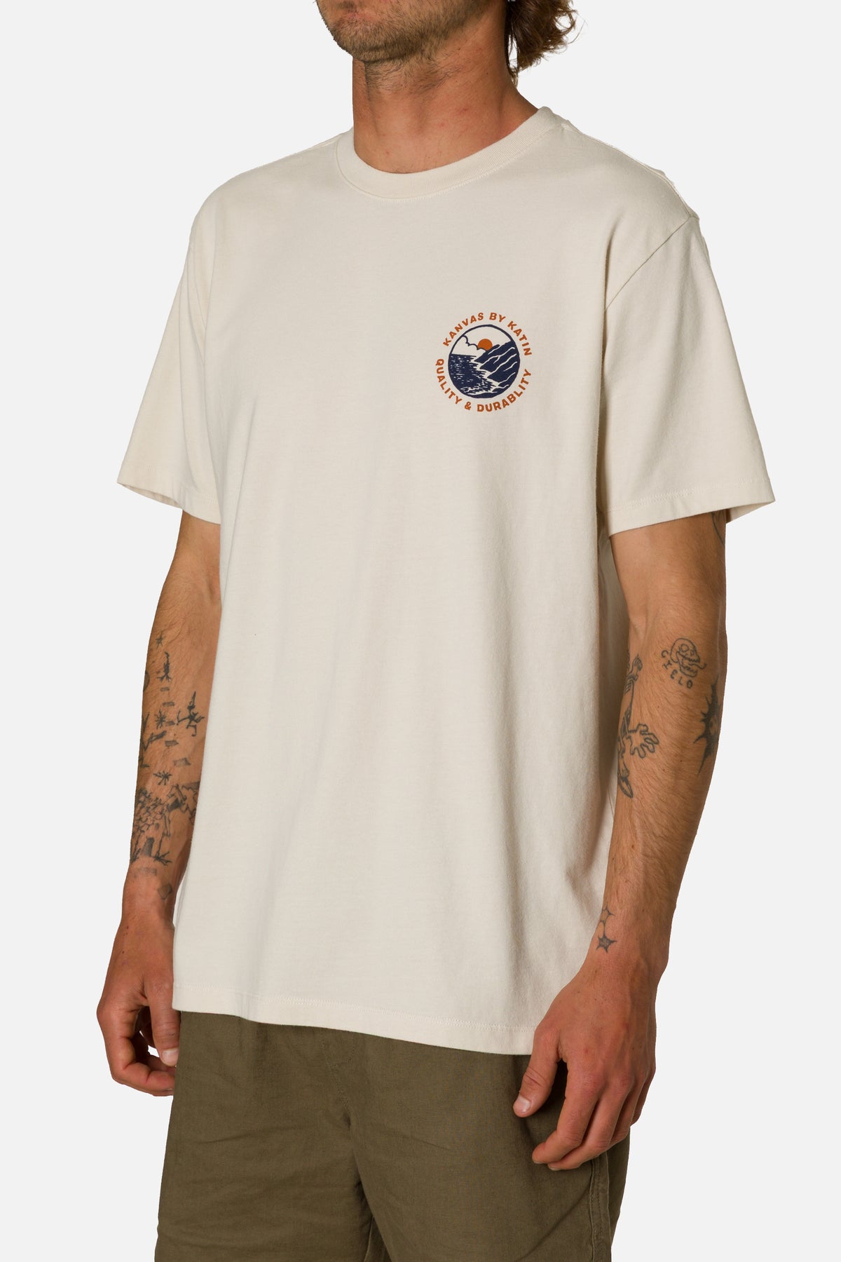 Man wearing a beige t-shirt with a logo on a white background