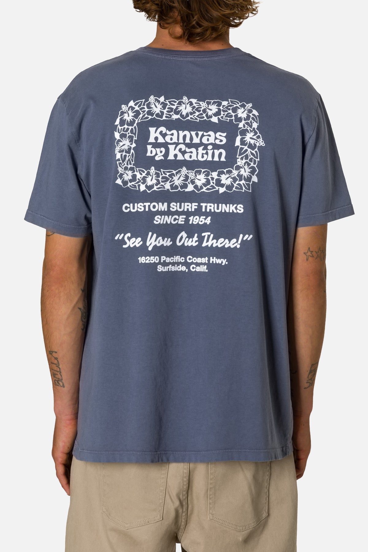 Person wearing a blue t-shirt with white text and branding on the back.