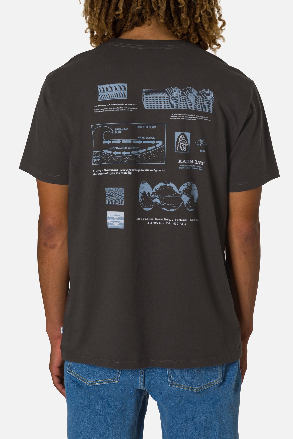 Person wearing a black t-shirt with technical drawings on the back, standing against a white background