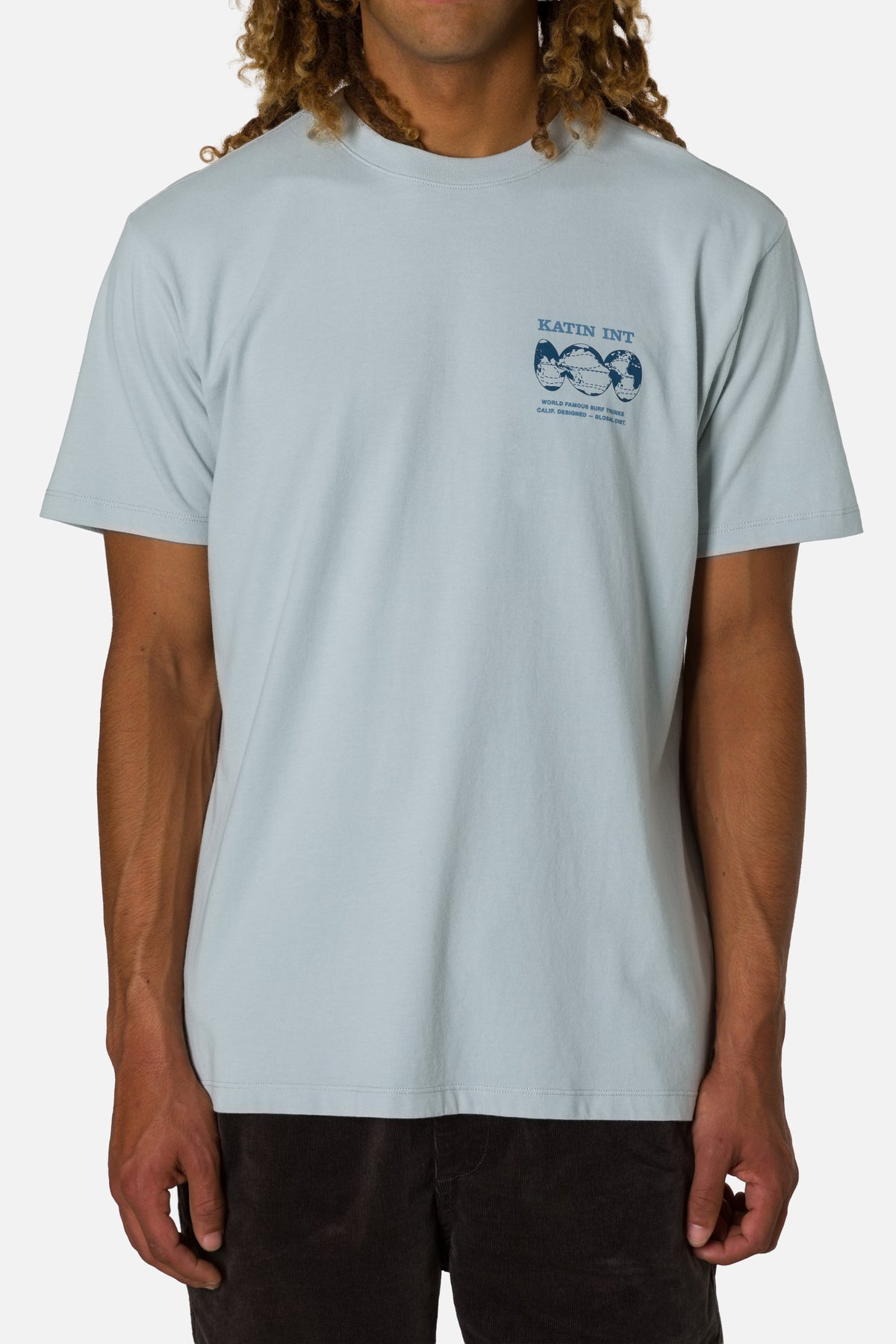 Person wearing a light blue t-shirt with a logo on a white background