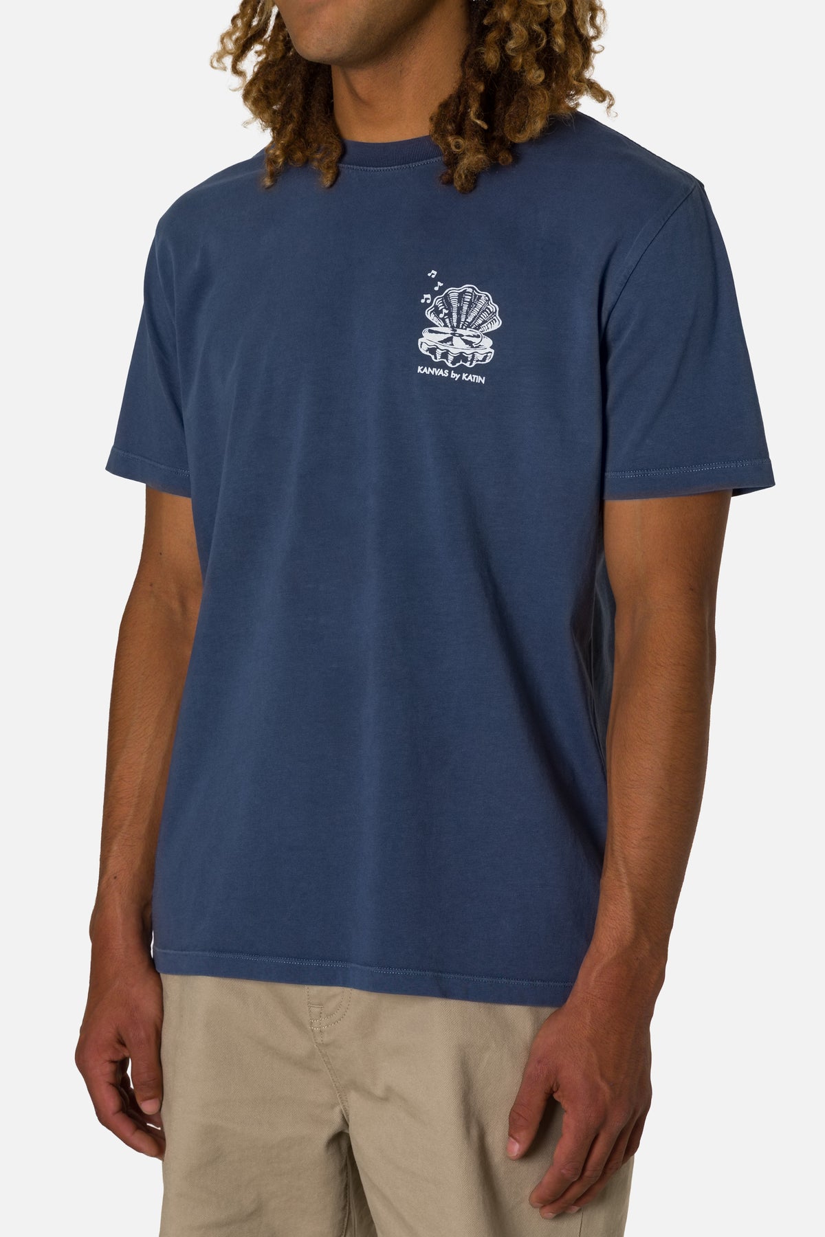 Person wearing a blue t-shirt with a white logo on a plain background