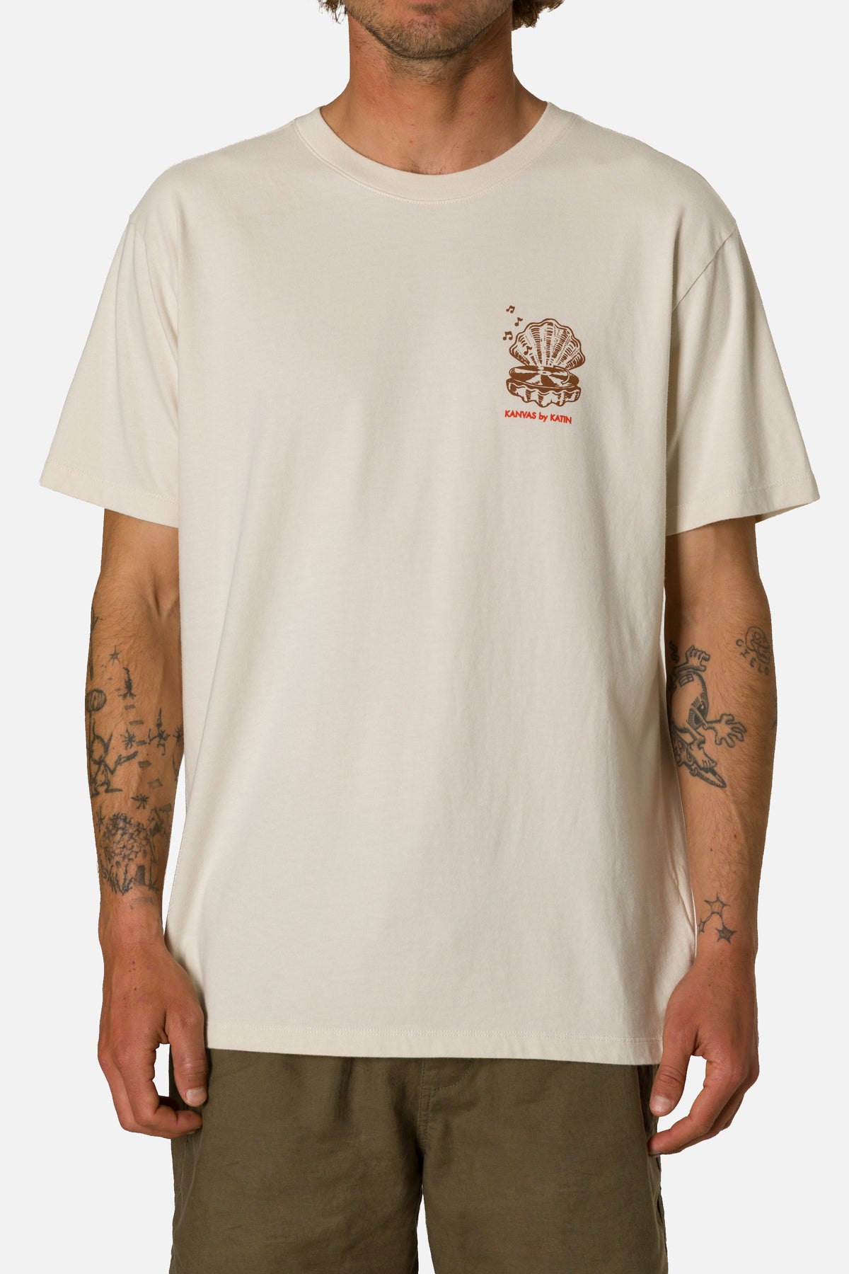 Person wearing a beige t-shirt with a logo on a white background