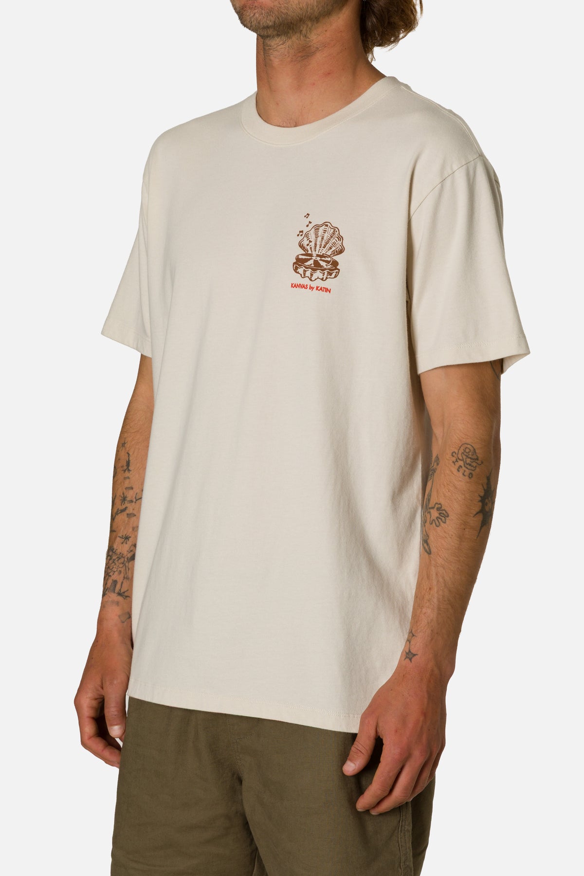 Person wearing a beige t-shirt with a logo on a white background