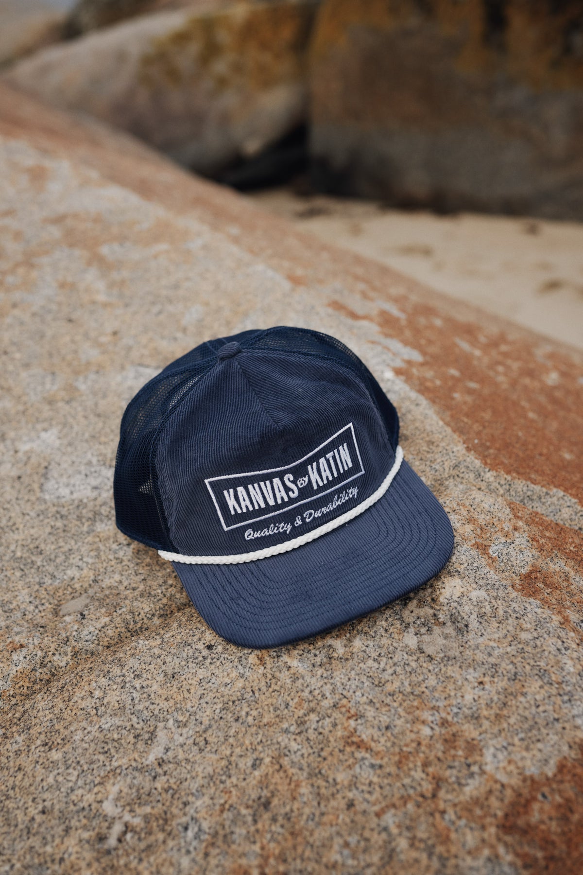 Navy blue cap with white text on a stone surface