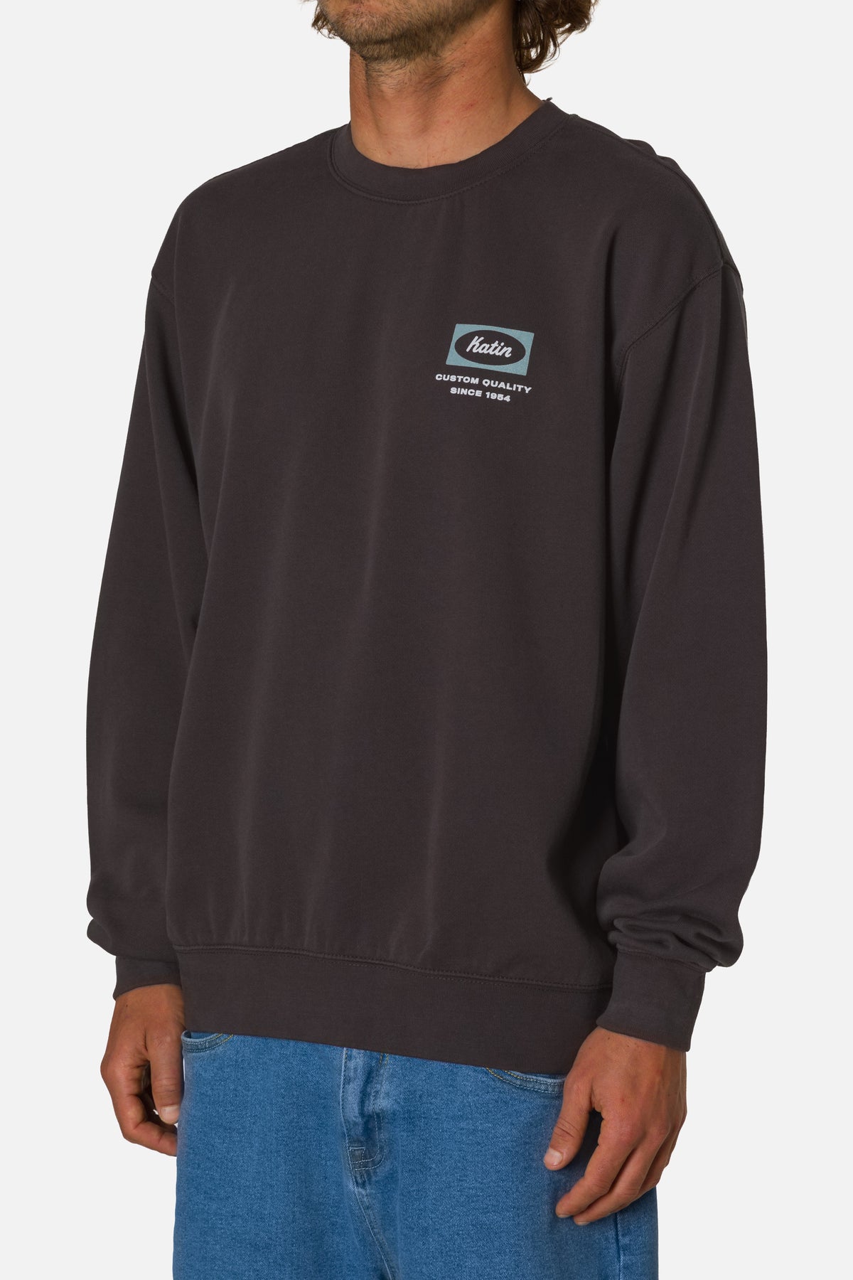 Person wearing a dark gray sweatshirt with a logo on a white background