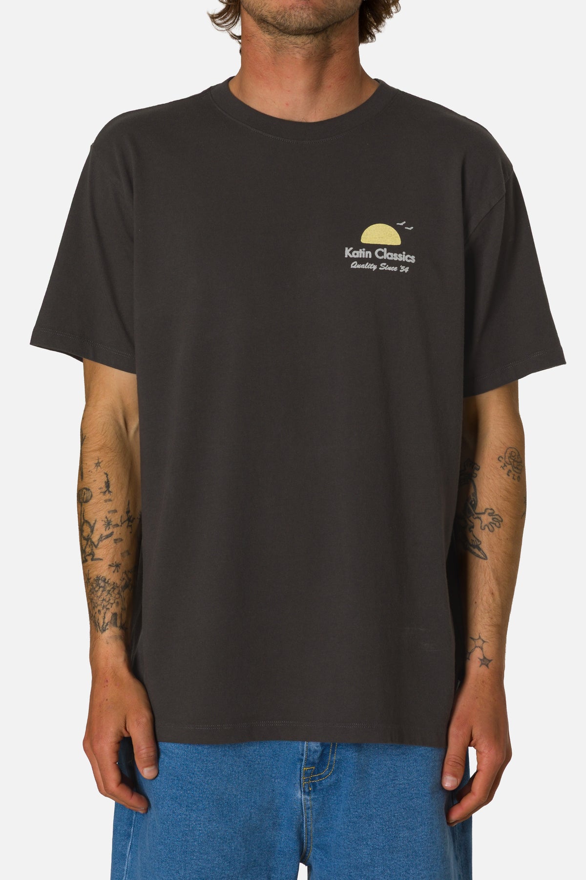 Person wearing a black t-shirt with a logo on a plain background