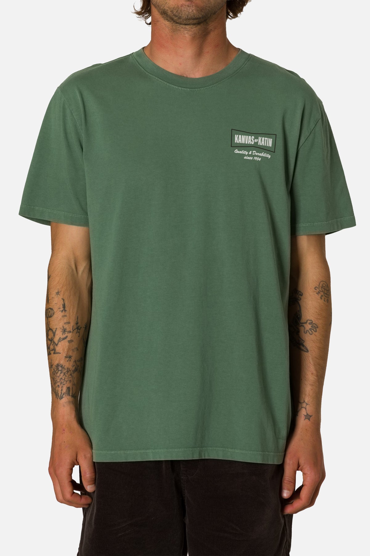 Person wearing a green t-shirt with a logo on a white background