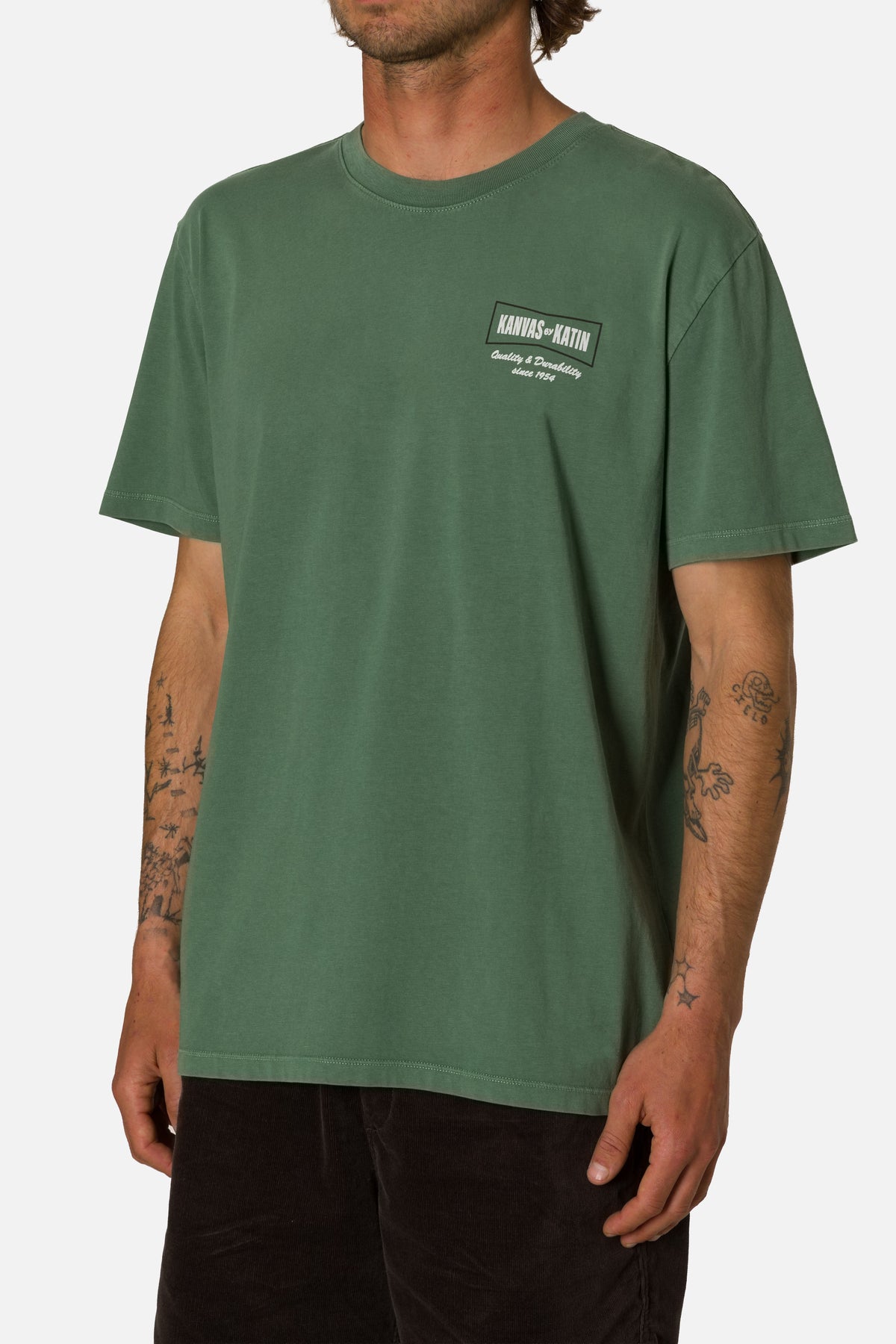 Person wearing a green t-shirt with a logo on a white background