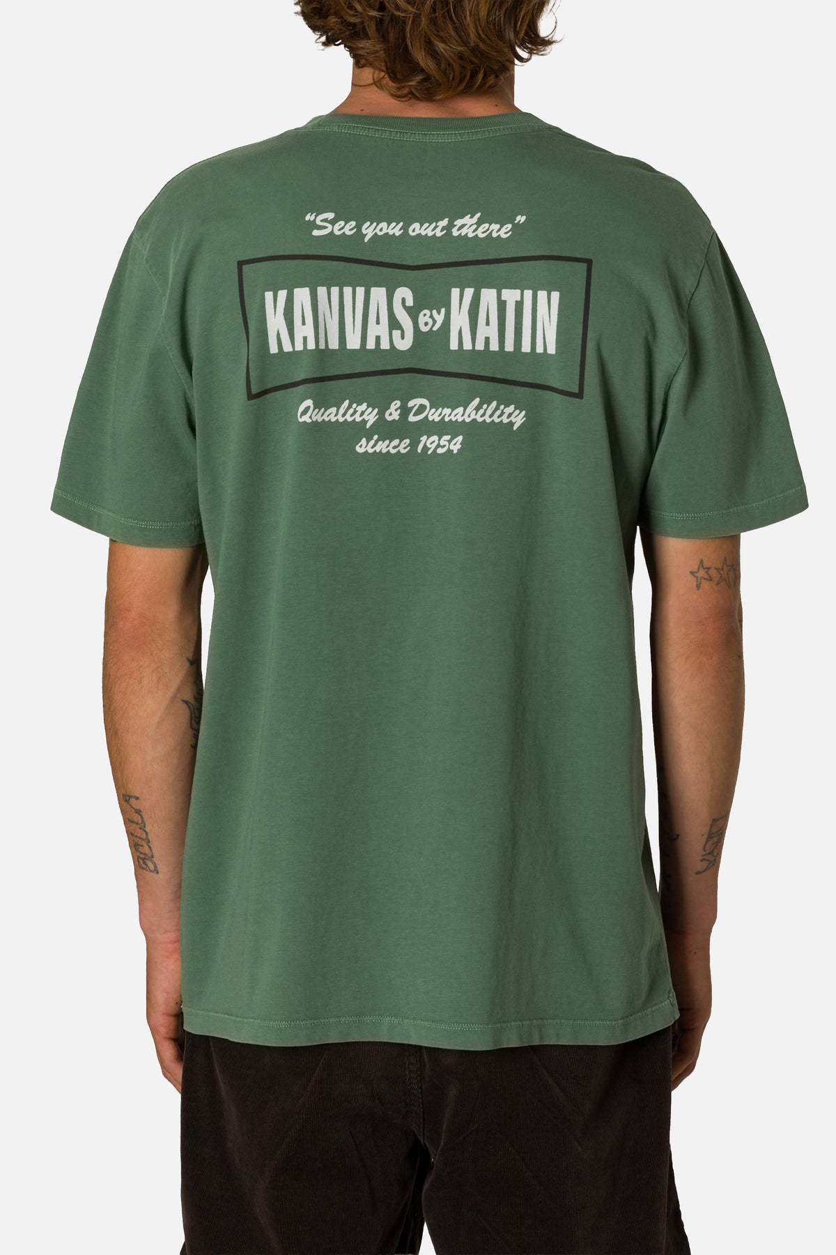 Green t-shirt with branding on the back worn by a person