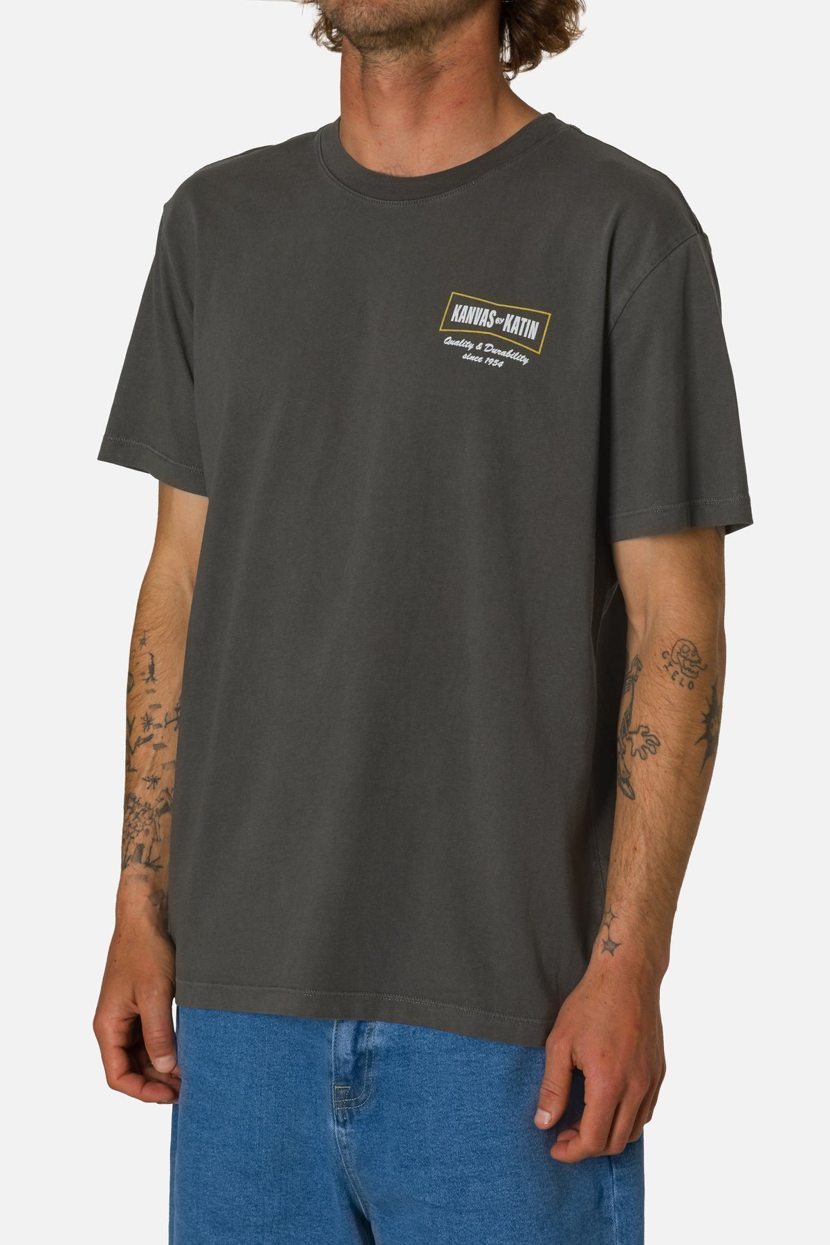 Person wearing a dark gray t-shirt with a logo on a white background