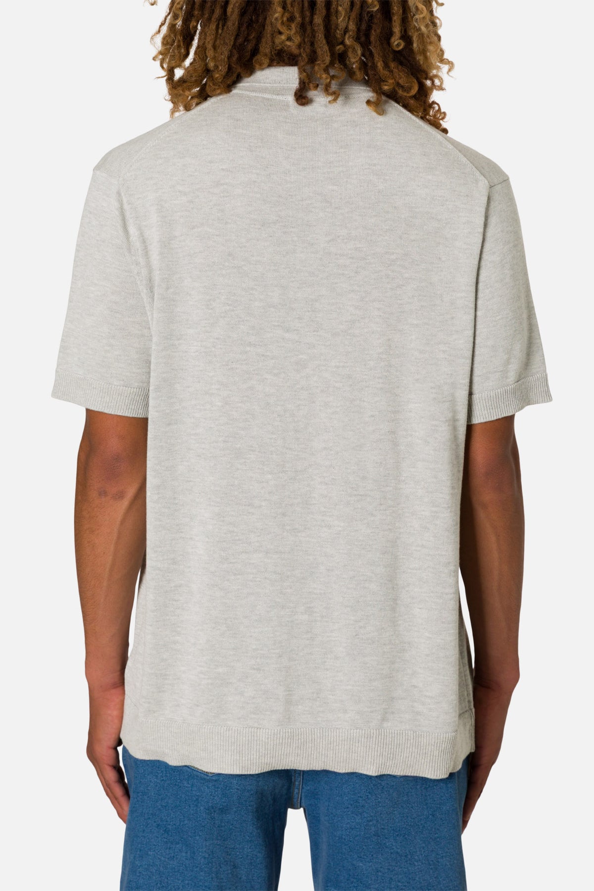 Person wearing a light gray shirt and blue pants on a white background