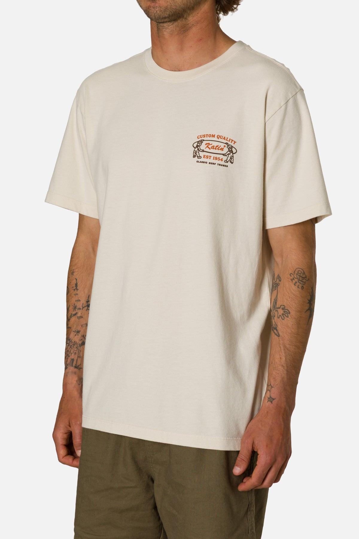 Person wearing a beige t-shirt with a logo on a white background