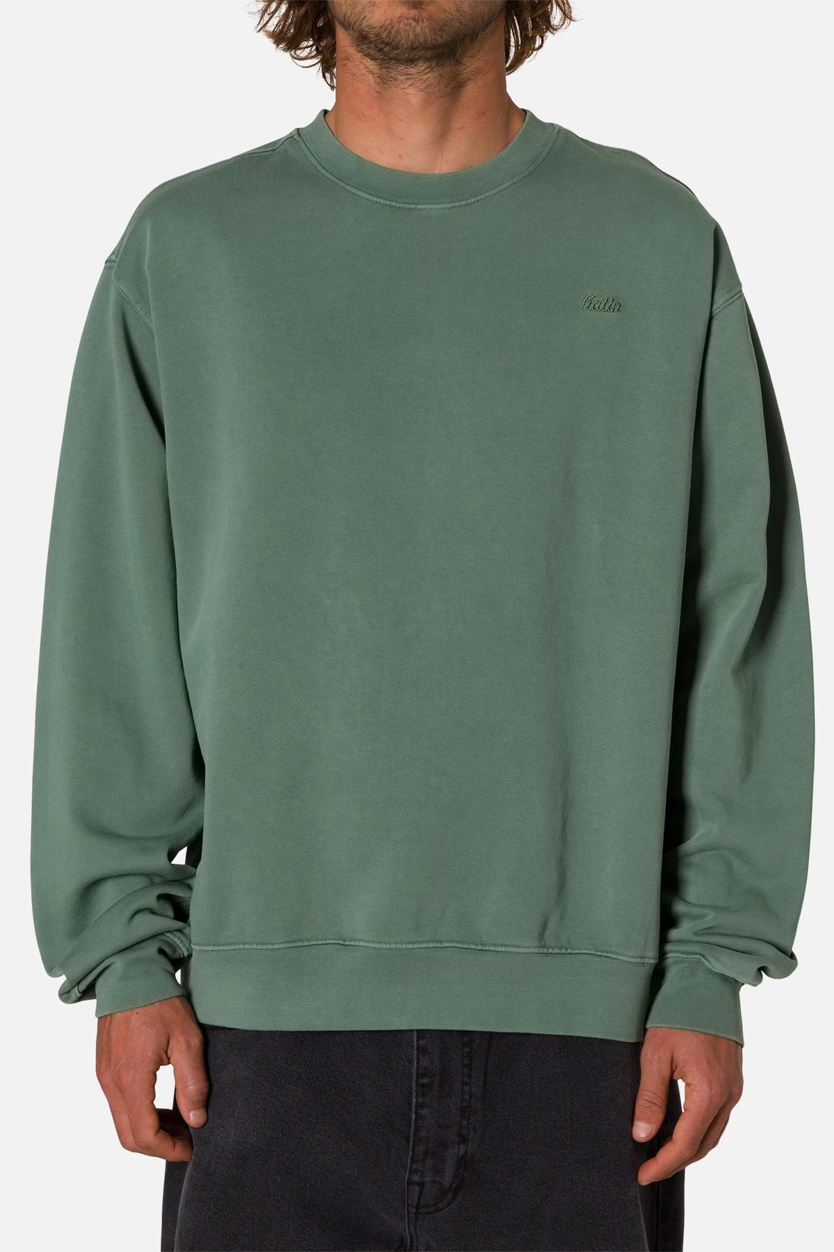 Person wearing a green sweatshirt with an embroidered Katin logo on a white background