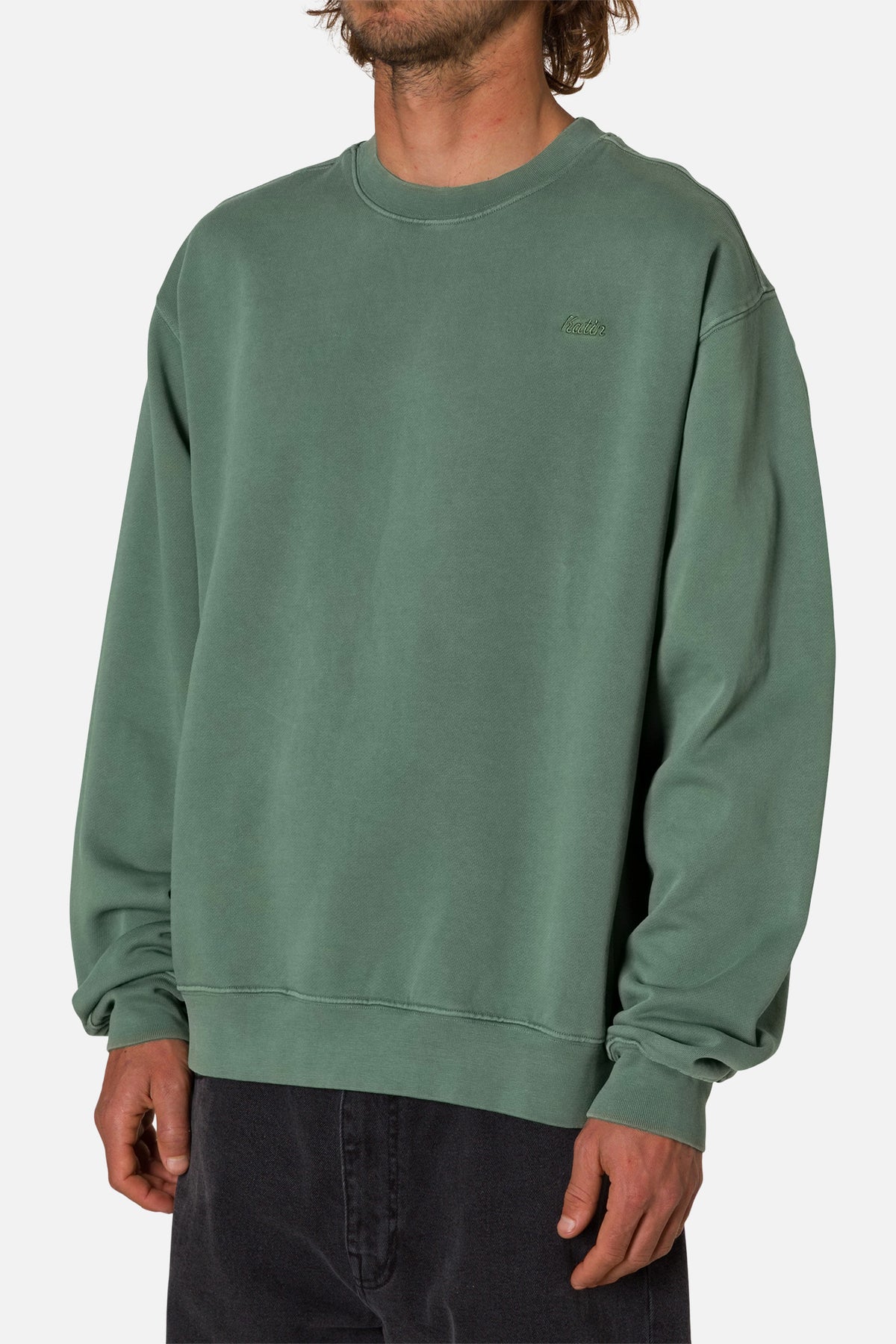 Person wearing a green sweatshirt with embroidered Katin logo on a white background