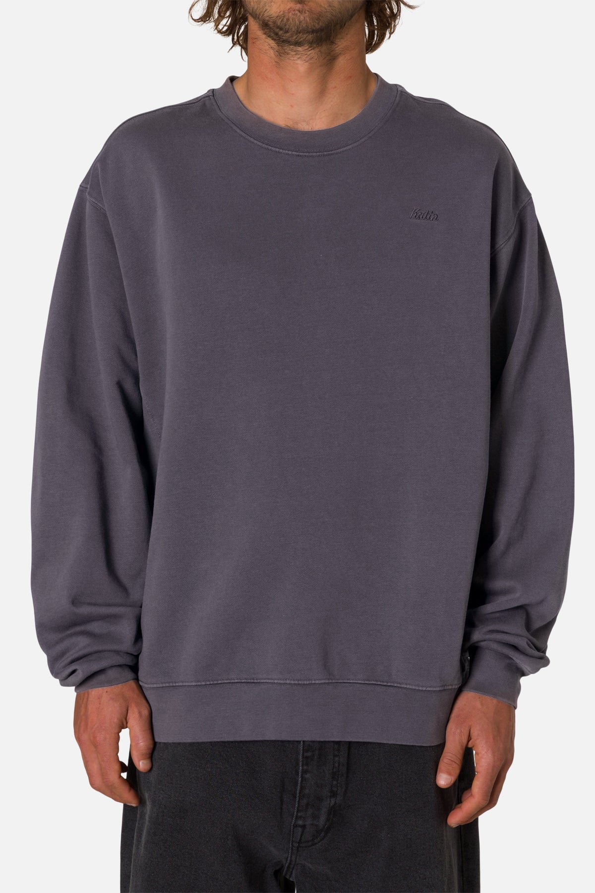 Person wearing a deep blue sweatshirt with an embroidered Katin logo on a white background