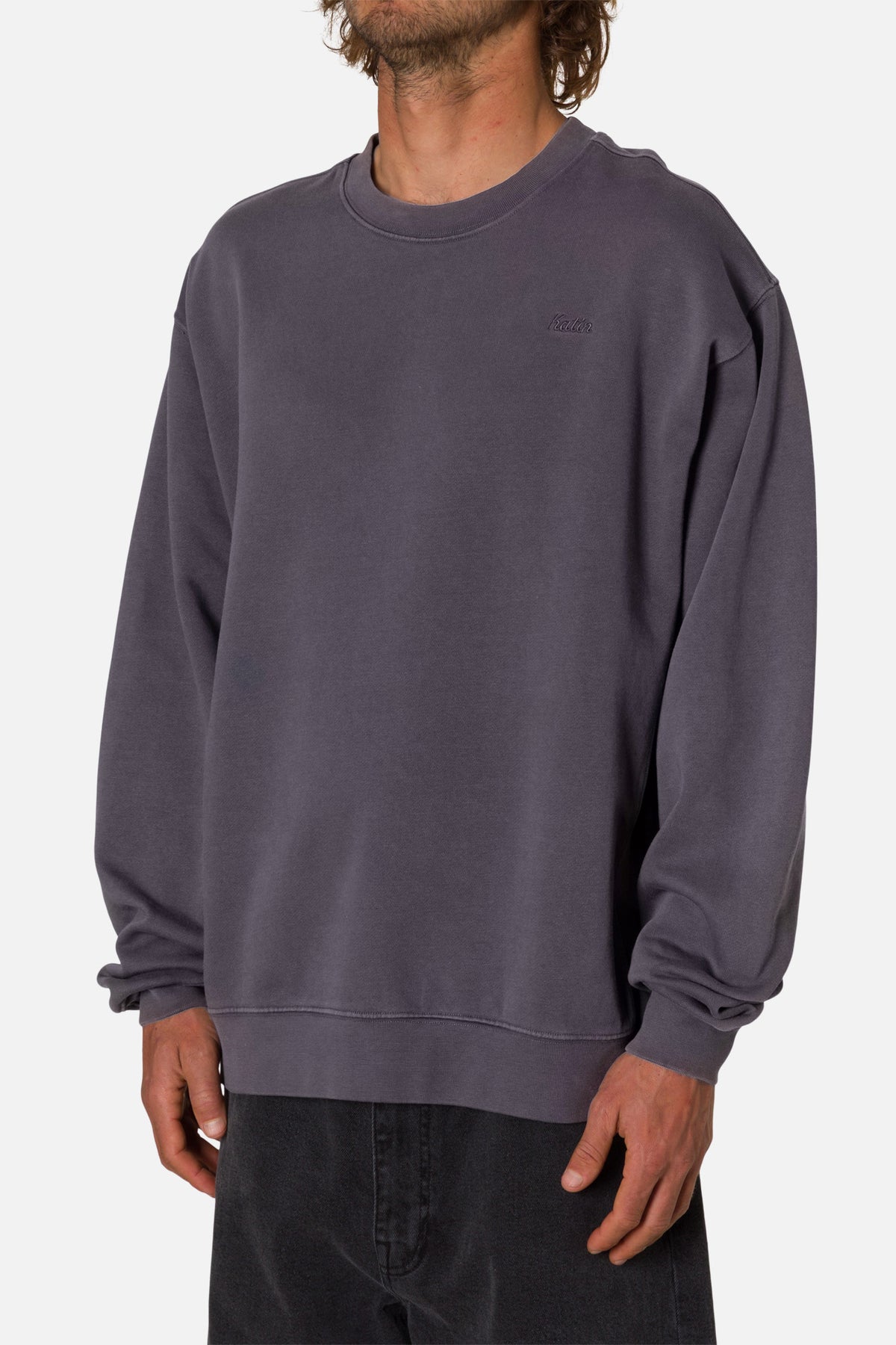 Person wearing a deep blue sweatshirt with an embroidered Katin logo on a white background