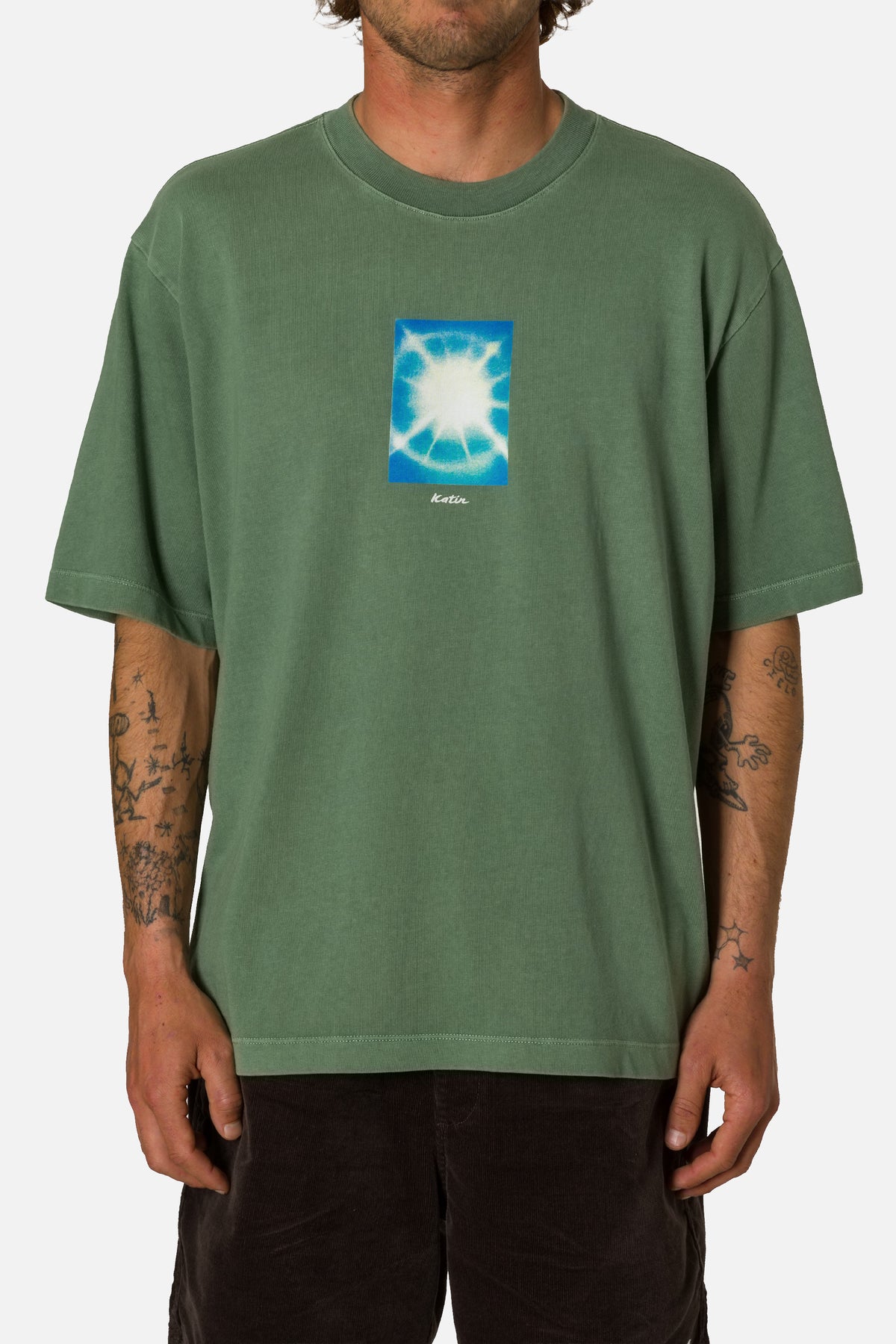 Person wearing a green t-shirt with a blue graphic on a white background
