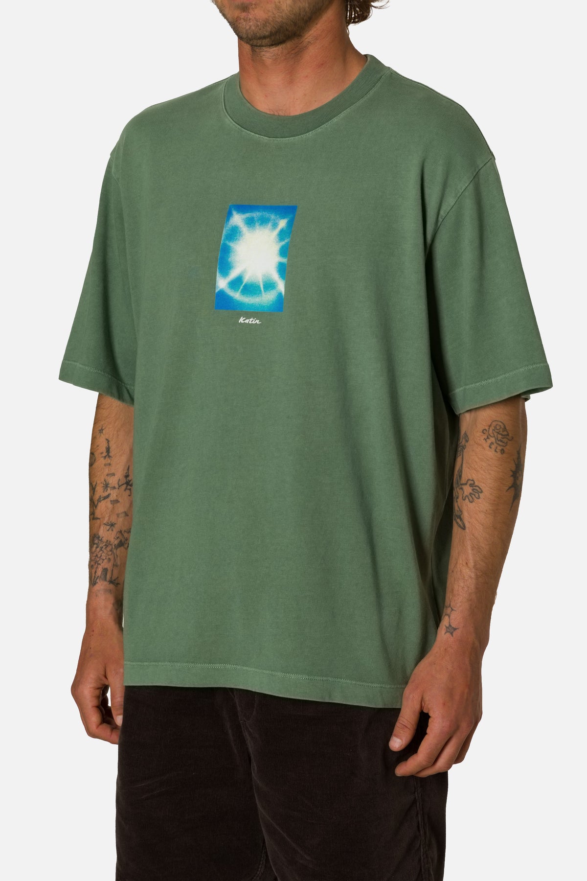 Person wearing a green t-shirt with a blue graphic on a white background