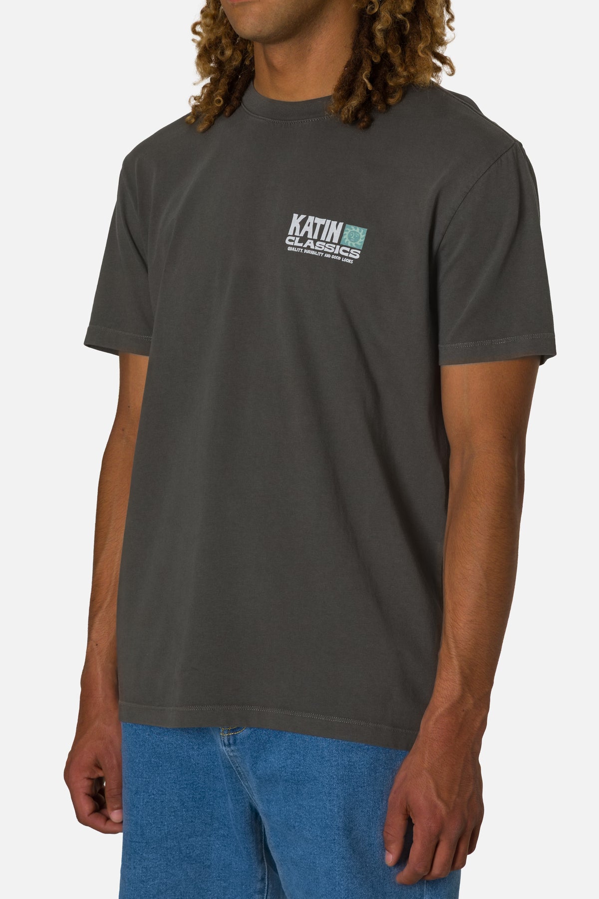 Person wearing a dark gray t-shirt with a logo on a white background