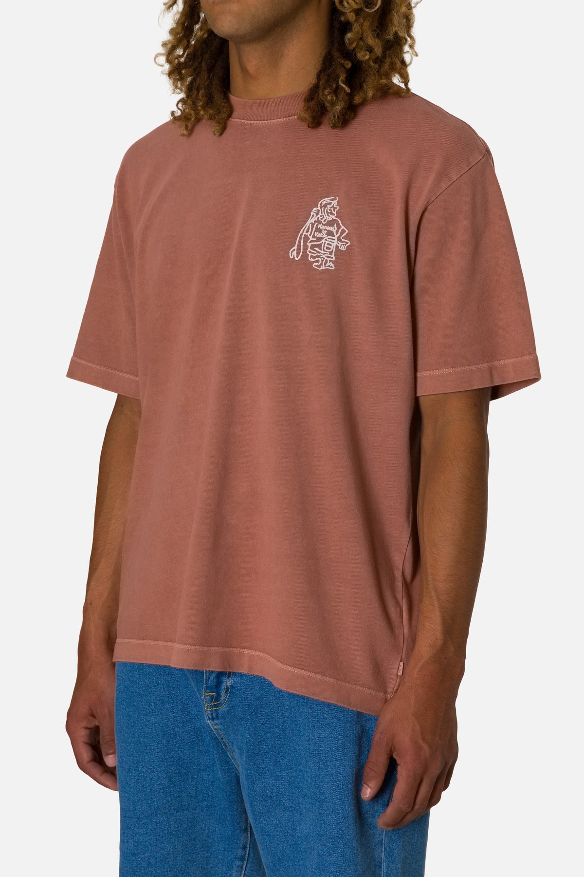 Person wearing a brown t-shirt with a small graphic on a white background