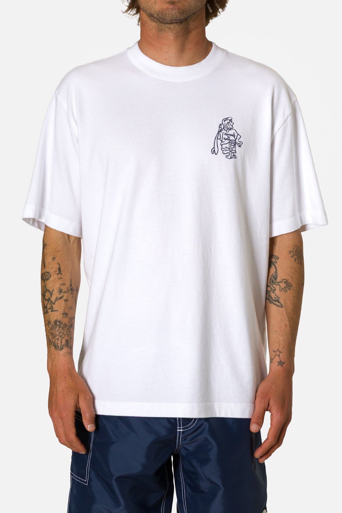 Person wearing a white t-shirt with a small graphic on the chest against a plain background