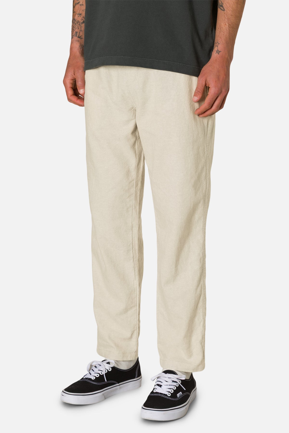 Person wearing beige pants and black sneakers on a white background