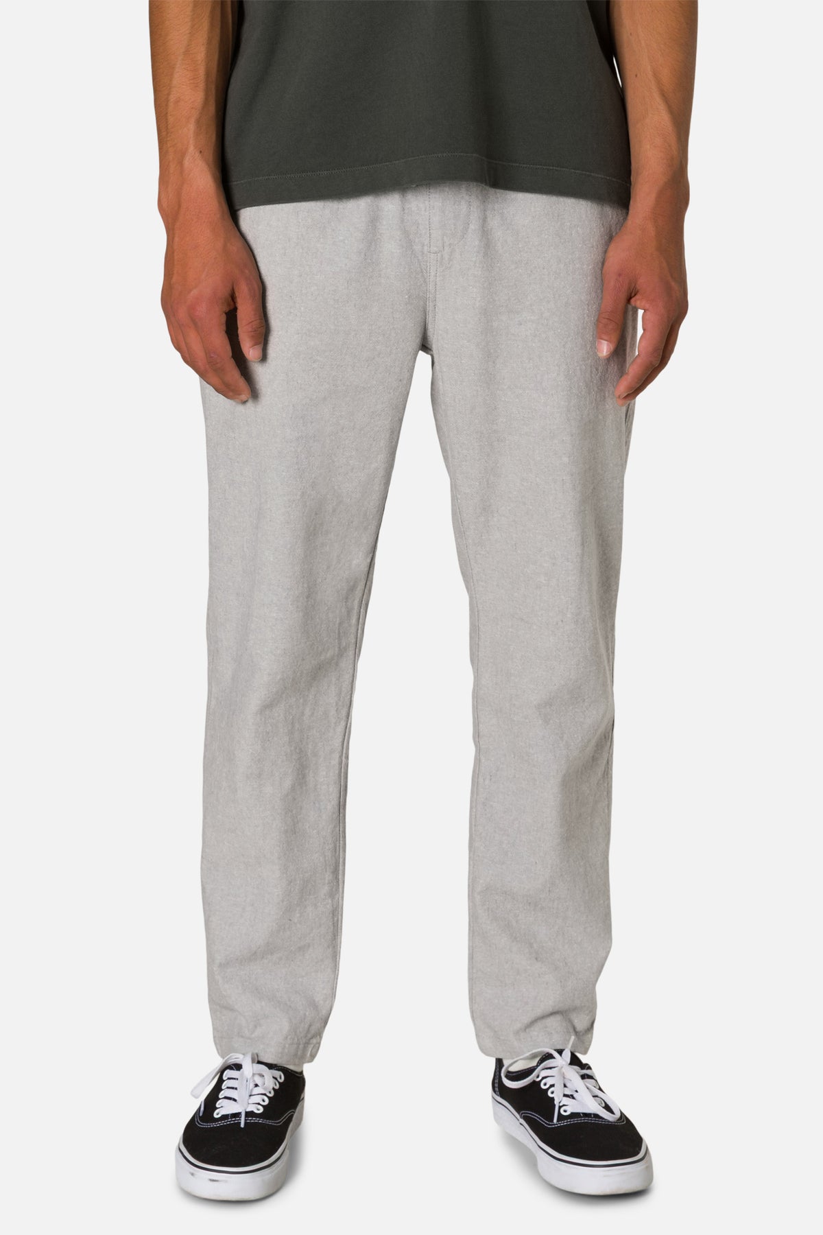 Person wearing gray sweatpants and black sneakers on a white background
