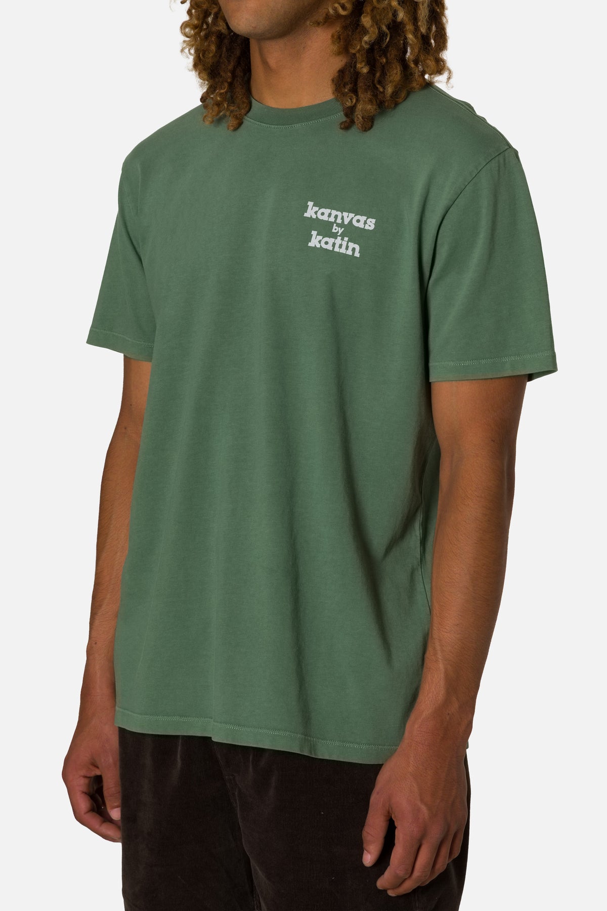 Person wearing a green t-shirt with a logo on a white background