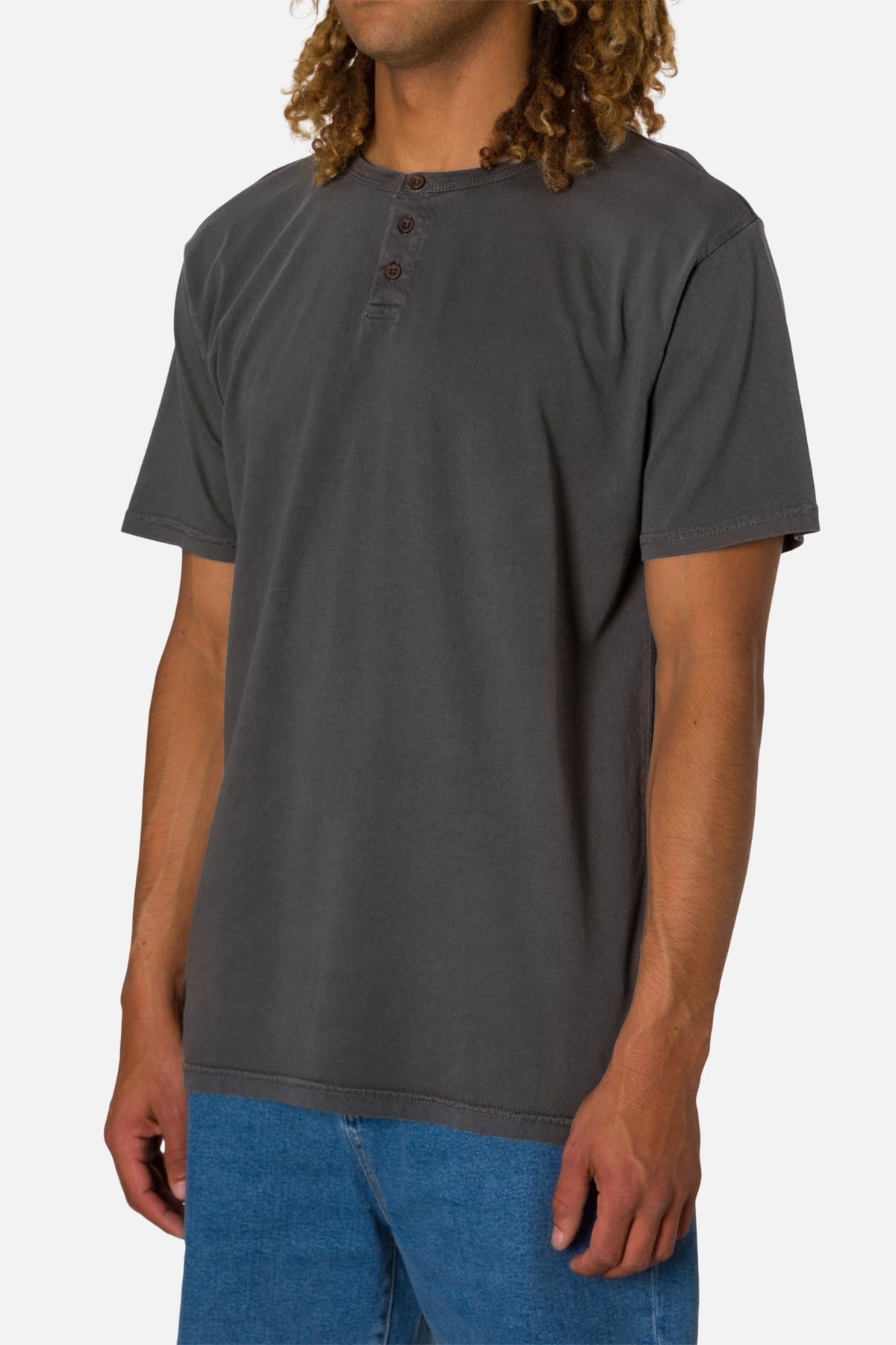 Person wearing a black wash henley shirt and blue jeans on a white 