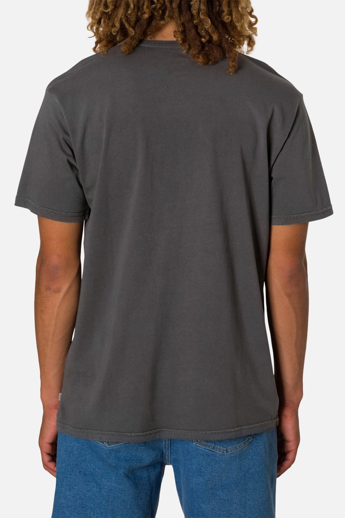 Person wearing a black wash henley shirt and blue jeans on a white 