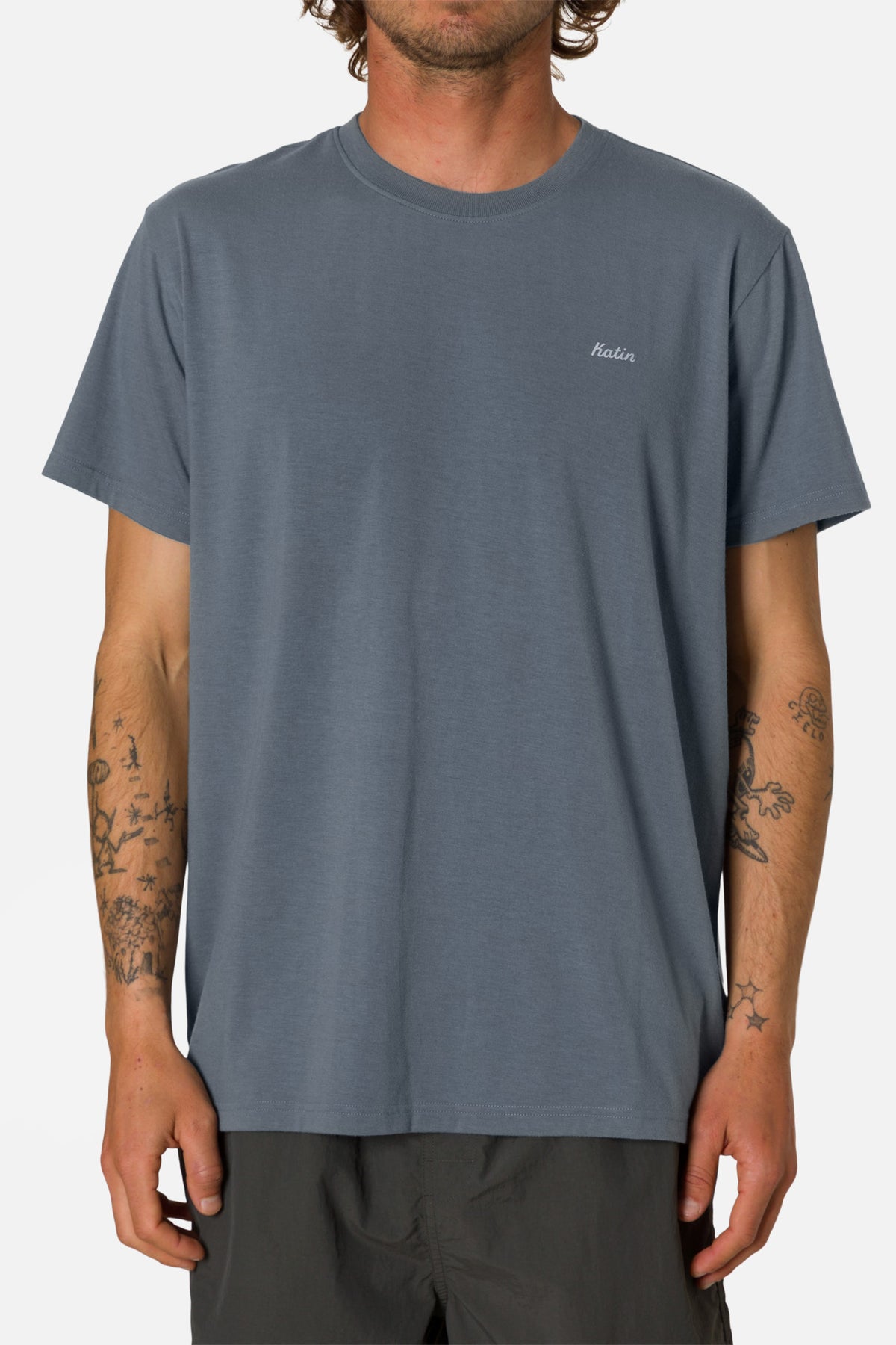 Person wearing a plain blue t-shirt with a brand logo on a white background